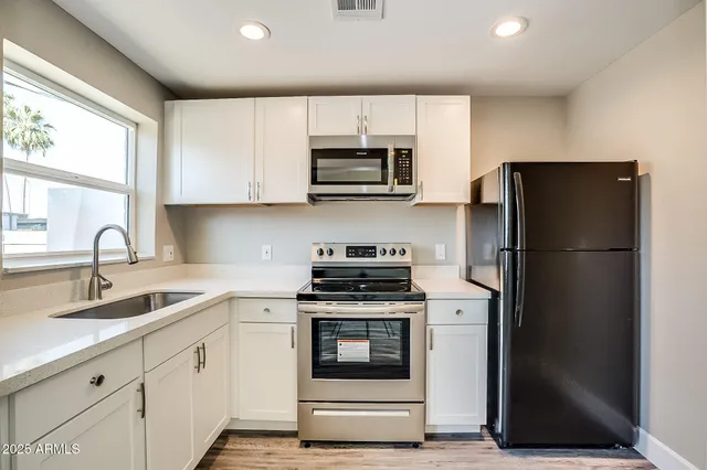 a kitchen with cabinets appliances a sink and a window