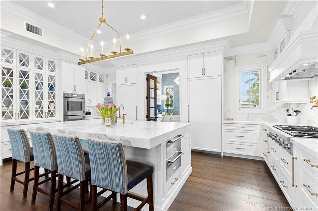 3 Island Road Stuart, FL 34996 - Photo 18 of 58 a kitchen with stainless steel appliances kitchen island granite countertop a table chairs and white cabinets