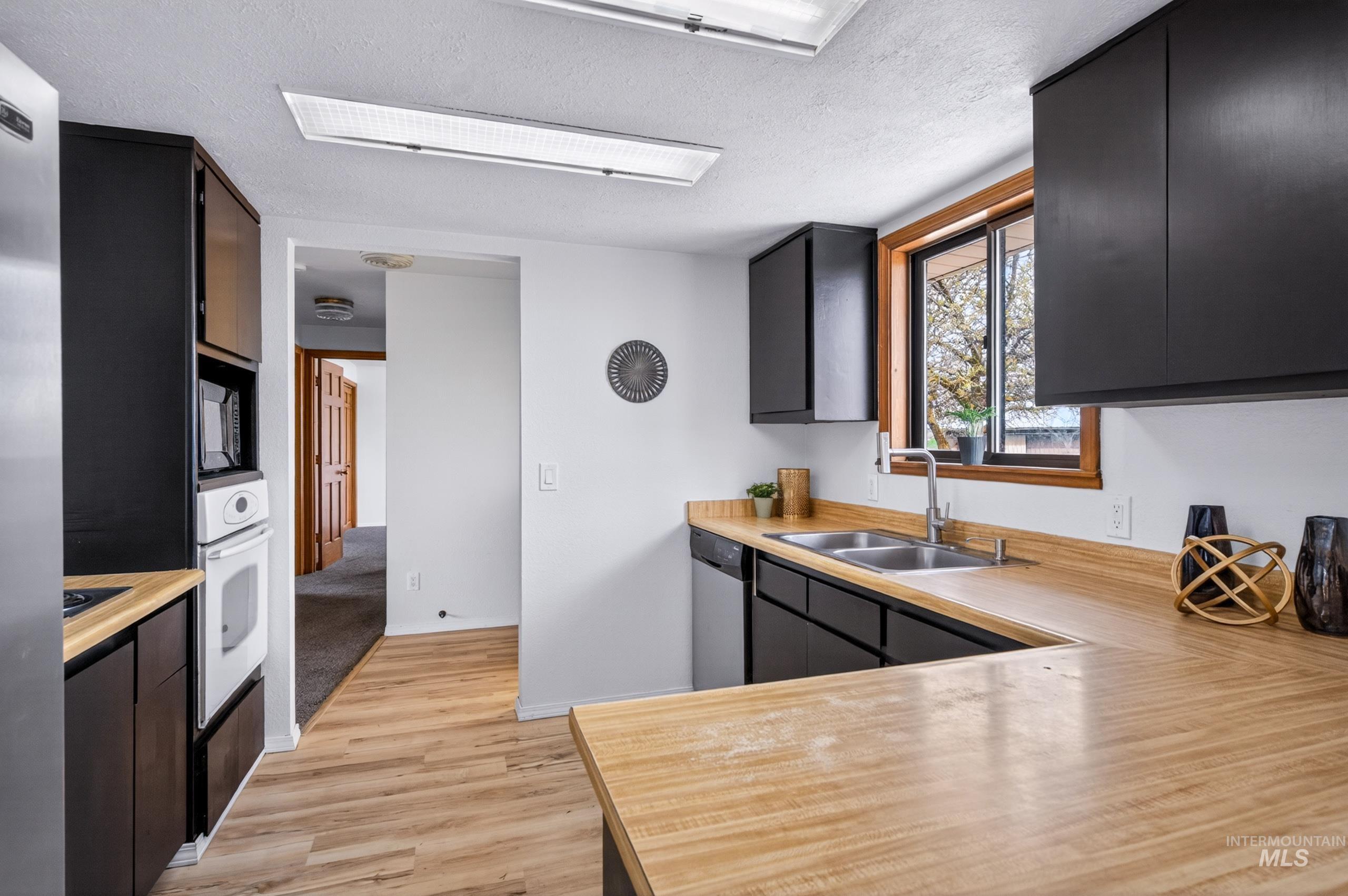 8989 Hillview Road Emmett, ID 83617 - Photo 11 of 50 Kitchen with dark cabinetry, a textured ceiling, light wood-style flooring, and stainless steel appliances