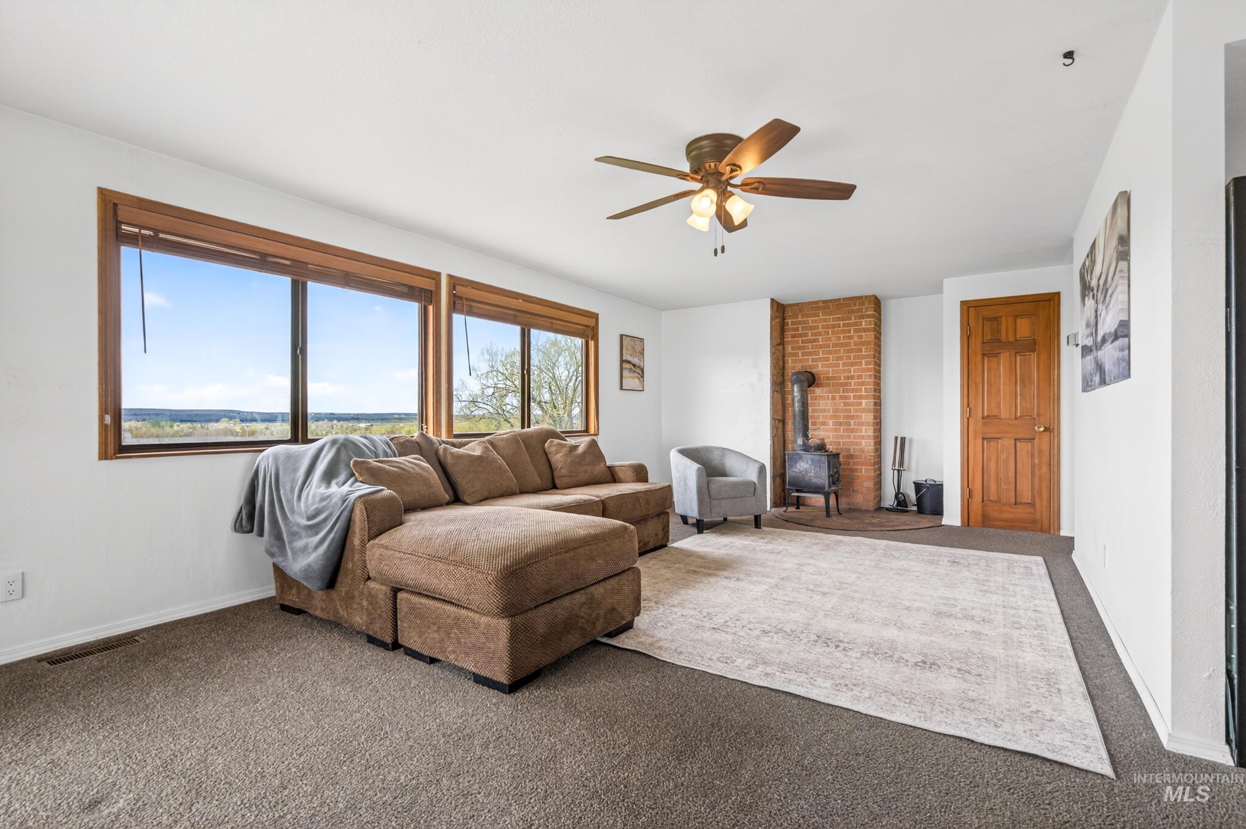 8989 Hillview Road Emmett, ID 83617 - Photo 16 of 50 Living area featuring a wood stove, ceiling fan, and carpet flooring
