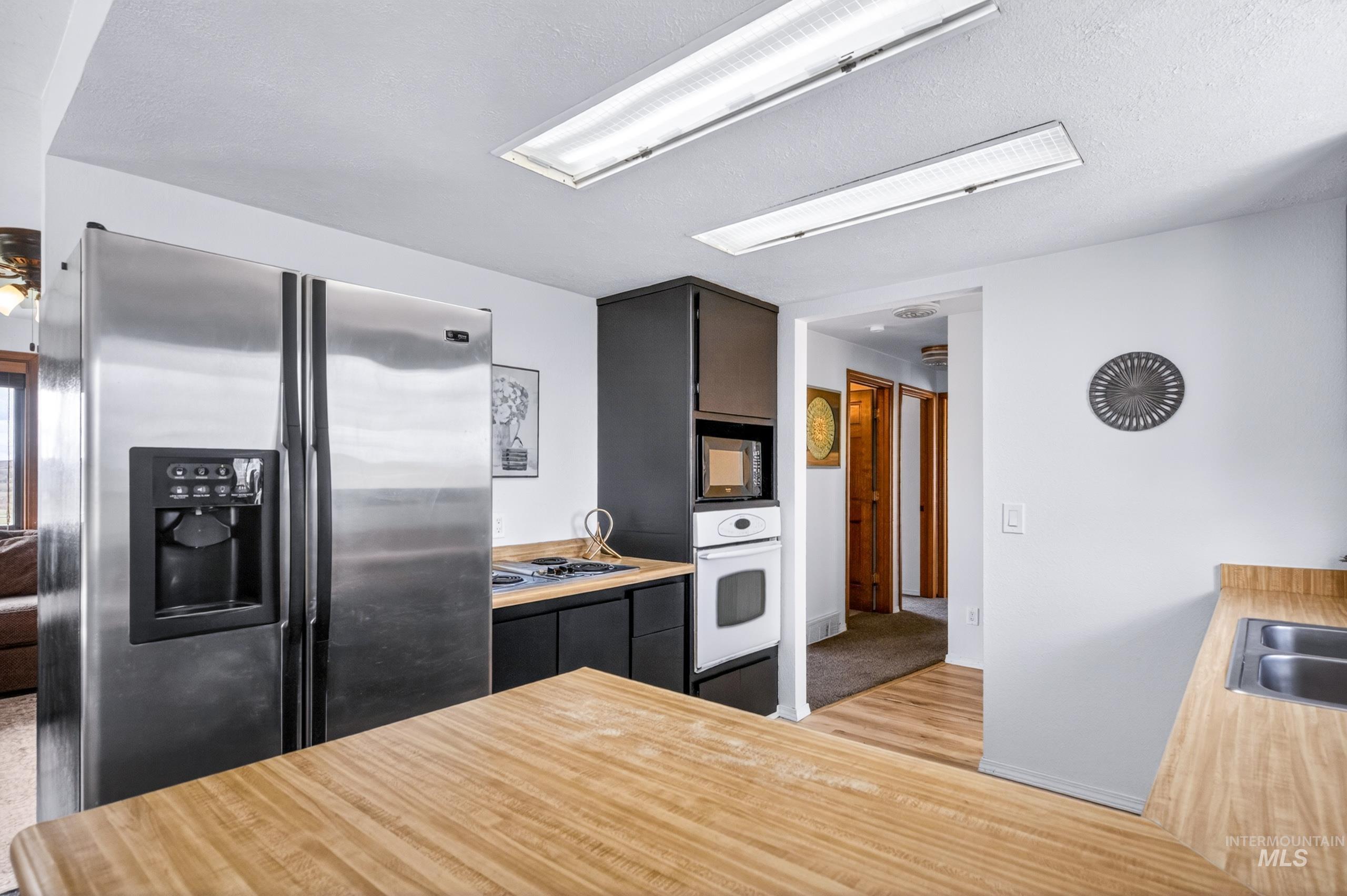 8989 Hillview Road Emmett, ID 83617 - Photo 10 of 50 Kitchen with stainless steel appliances, light countertops, light wood finished floors, a peninsula, and dark cabinets
