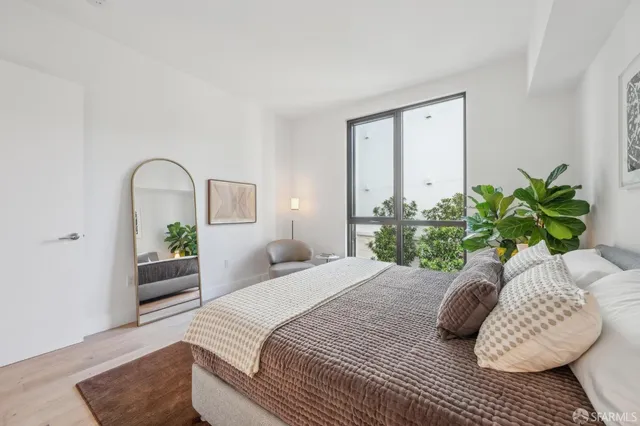 a bedroom with a large bed and a potted plant