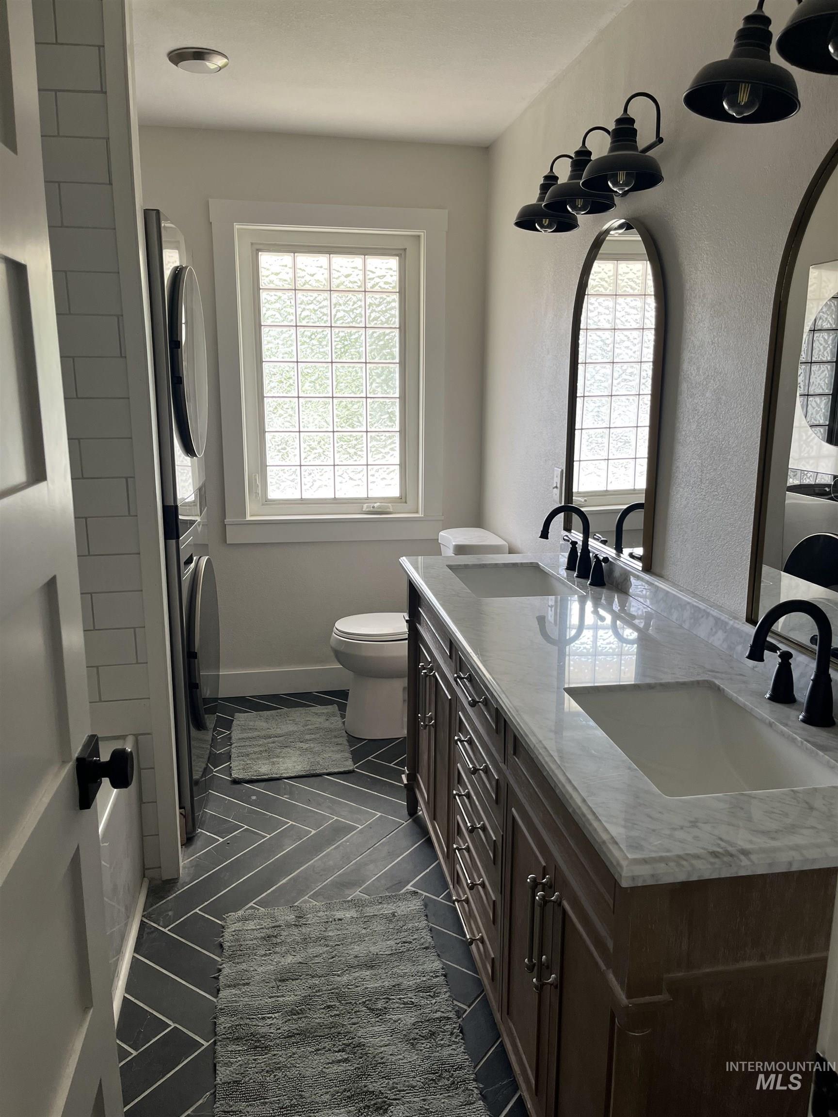 1024 El Cajon Street Moscow, ID 83843 - Photo 14 of 49 Bathroom featuring stacked washing machine and dryer, healthy amount of natural light, double vanity, and a textured wall