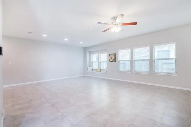 an empty room with windows and ceiling fan