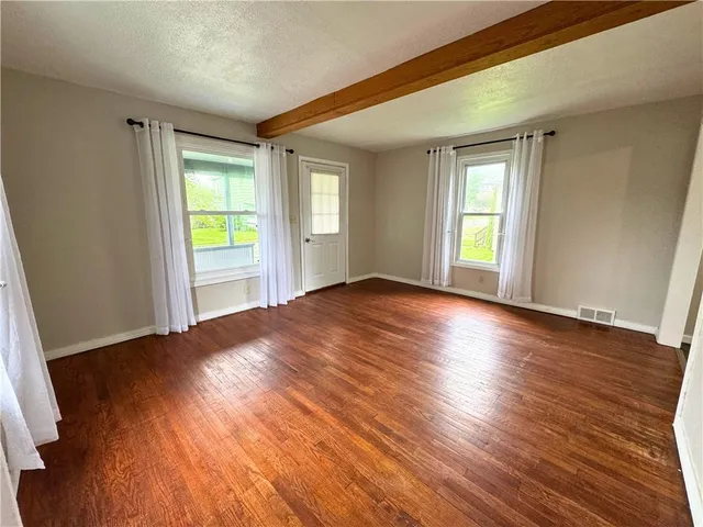 an empty room with window and wooden floor
