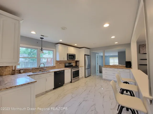 a large kitchen with kitchen island a stove a sink a refrigerator and a dining table with wooden cabinet