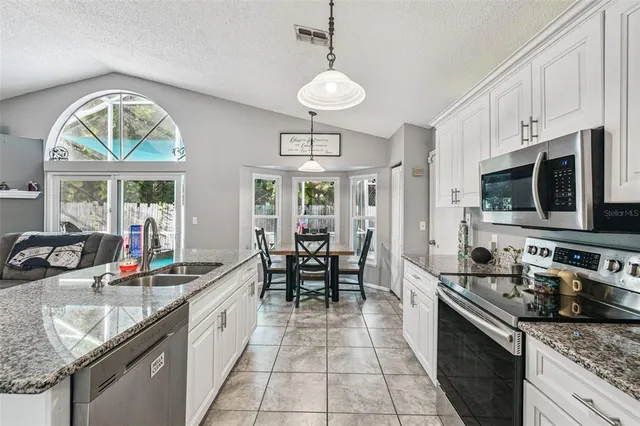 a kitchen with stainless steel appliances granite countertop a stove a sink dishwasher a dining table and chairs with wooden floor