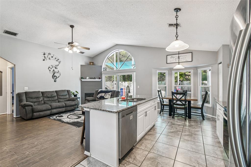 7501 Fawn Lake Road New Port Richey, FL 34655 - Photo 10 of 27 a kitchen with stainless steel appliances granite countertop a stove a sink dishwasher a dining table and chairs with wooden floor