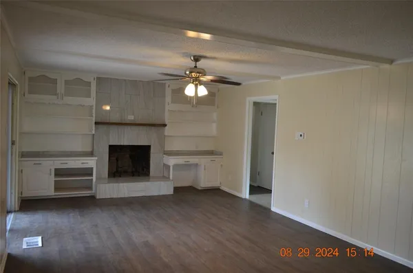a view of a livingroom with a fireplace a ceiling fan and brick wall