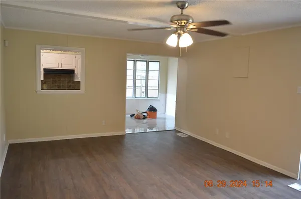 a view of an empty room with window and wooden floor