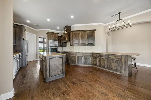 a kitchen with kitchen island granite countertop a stove top oven a sink a counter space and cabinets
