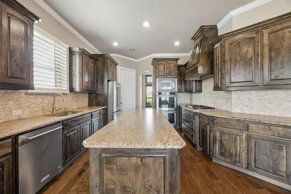 a kitchen with stainless steel appliances granite countertop a kitchen island hardwood floor sink stove and granite counter top