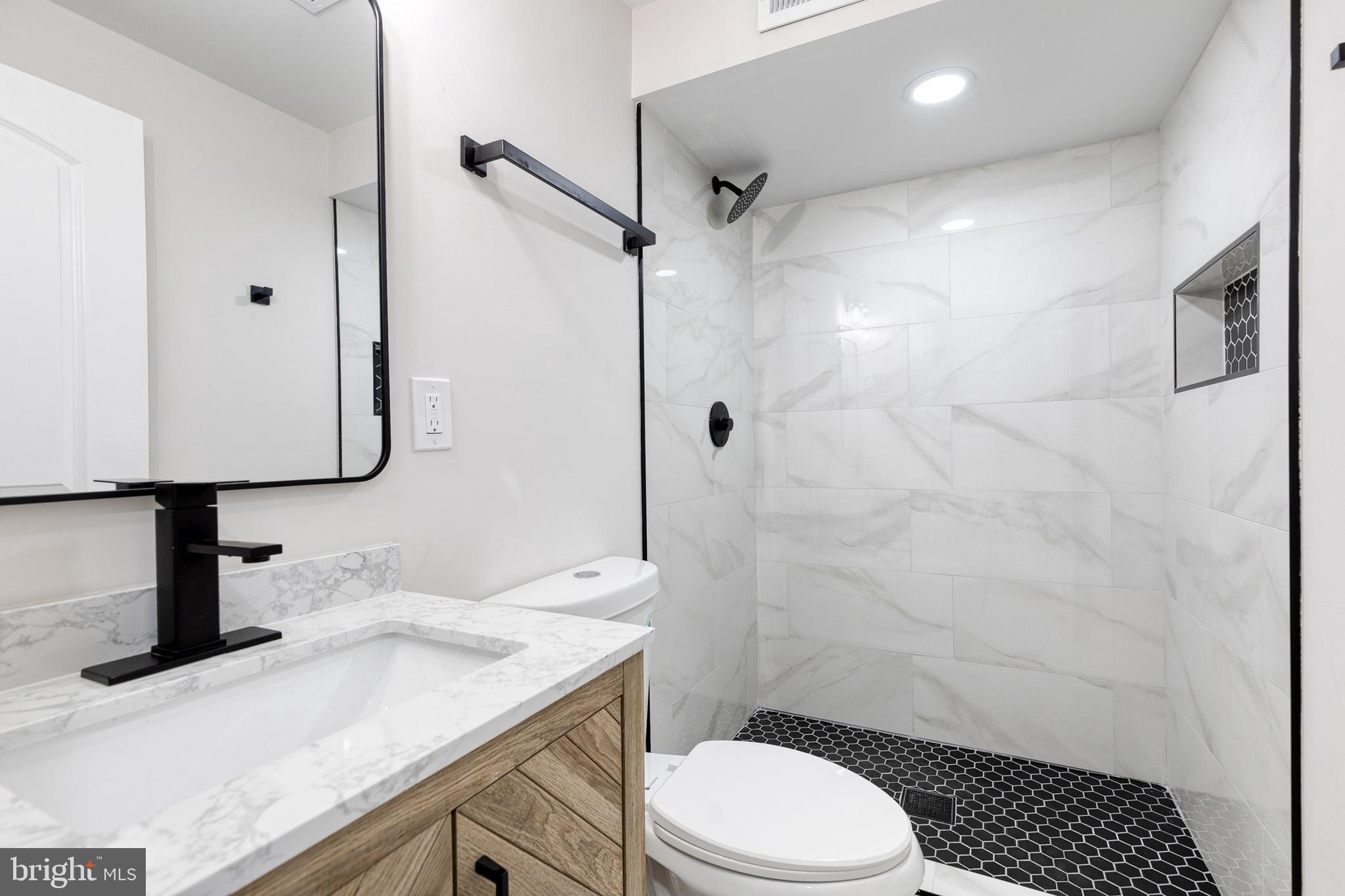 3721 Manchester Avenue Baltimore, MD 21215 - Photo 32 of 36 a bathroom with a granite countertop sink toilet a mirror and shower
