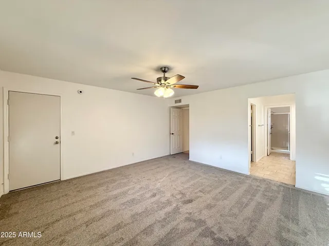 an empty room with closet and a chandelier fan