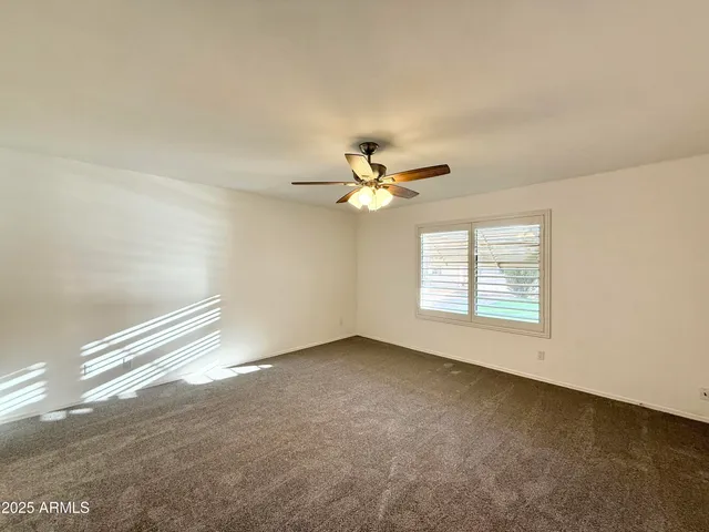 an empty room with a window and a fan