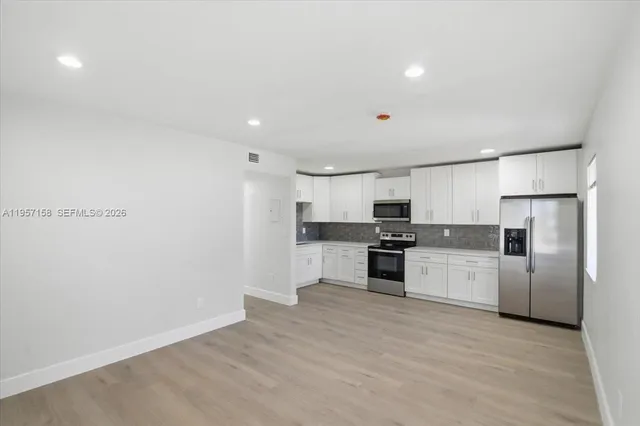 a kitchen with a refrigerator and white cabinets