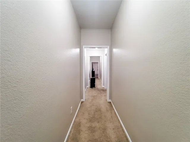 a view of a hallway with wooden floor and a bathroom