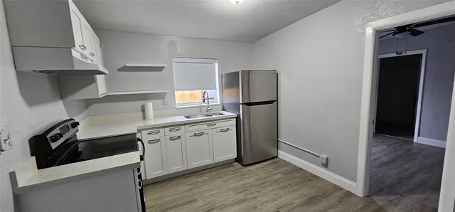 a kitchen with stainless steel appliances a sink a stove a refrigerator and cabinets