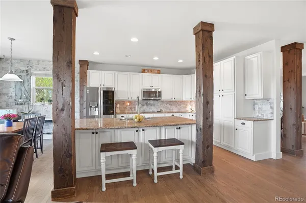 a kitchen with white cabinets and chairs