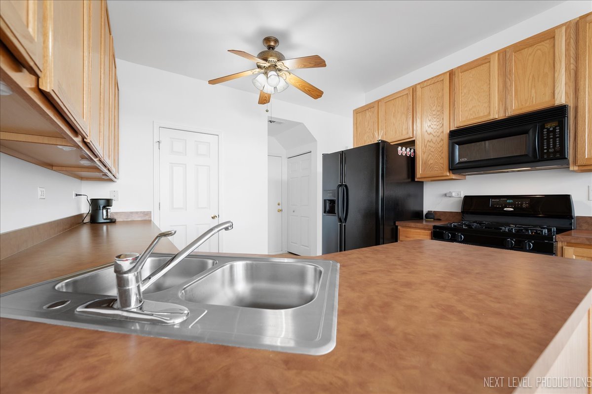557 Springbrook Trail North Oswego, IL 60543 - Photo 7 of 25 a kitchen with stainless steel appliances a sink a microwave a refrigerator and cabinets