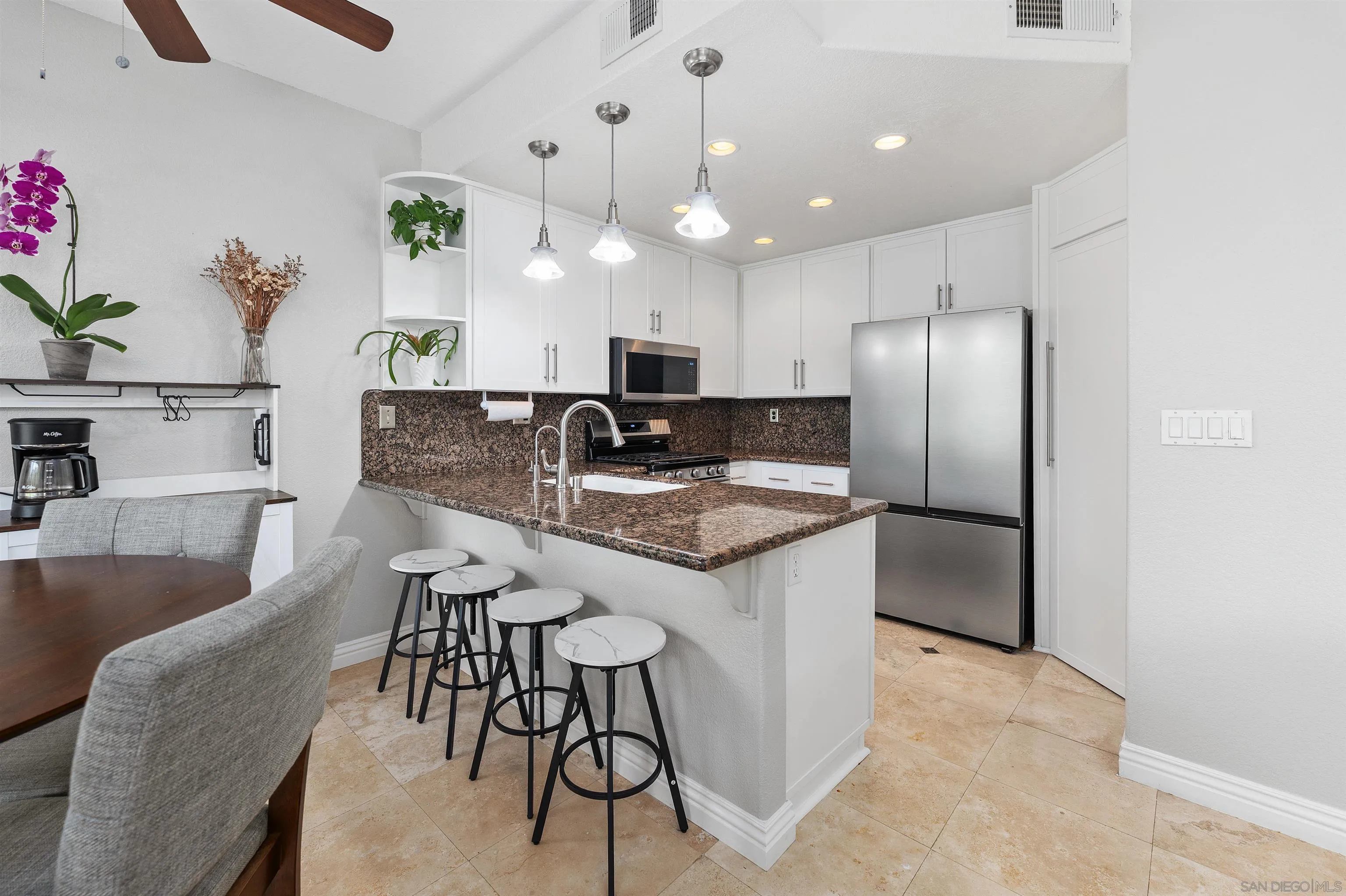 1571 Corte Daniel Oceanside, CA 92056 - Photo 13 of 44 a kitchen with kitchen island granite countertop a table chairs refrigerator and microwave