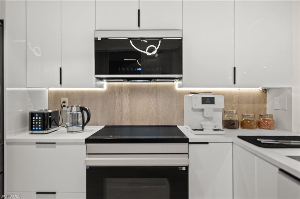 1100 Pine Ridge Road, Unit B103 Naples, FL 34108 - Photo 9 of 38 a kitchen with a stove and a microwave