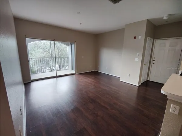 an empty room with wooden floor and windows with curtains