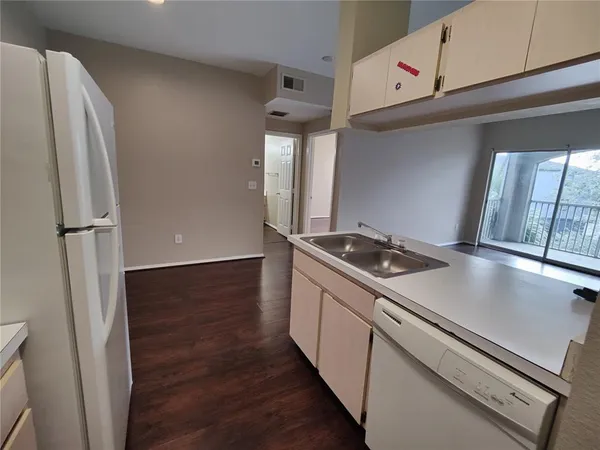 a view of a kitchen with refrigerator and wooden floor