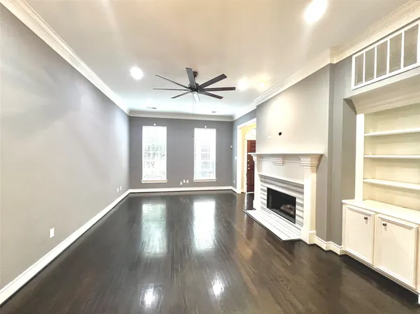 a view of an empty room with a fireplace and wooden floor
