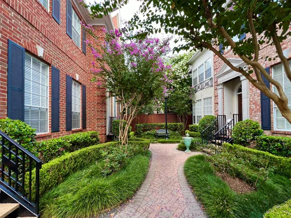 a front view of a house with garden and trees