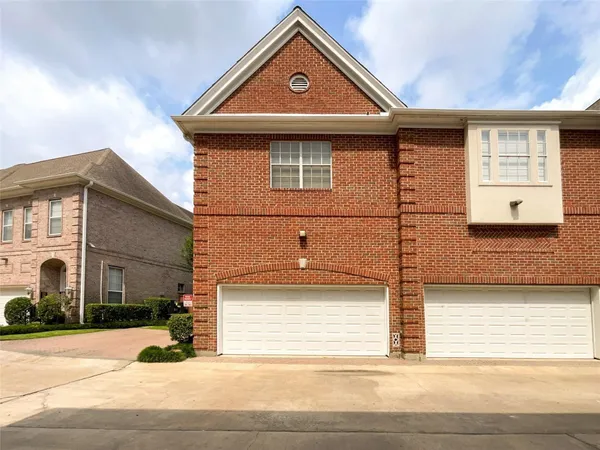 a view of a house with a small yard and large parking space
