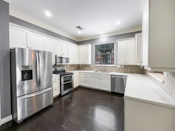 a kitchen with granite countertop white cabinets and stainless steel appliances