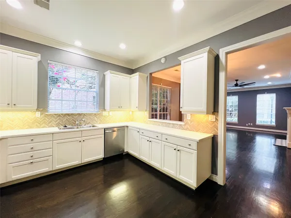 a large white kitchen with wooden floor and a window