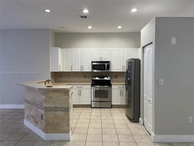 a kitchen with stainless steel appliances granite countertop a refrigerator and a stove top oven