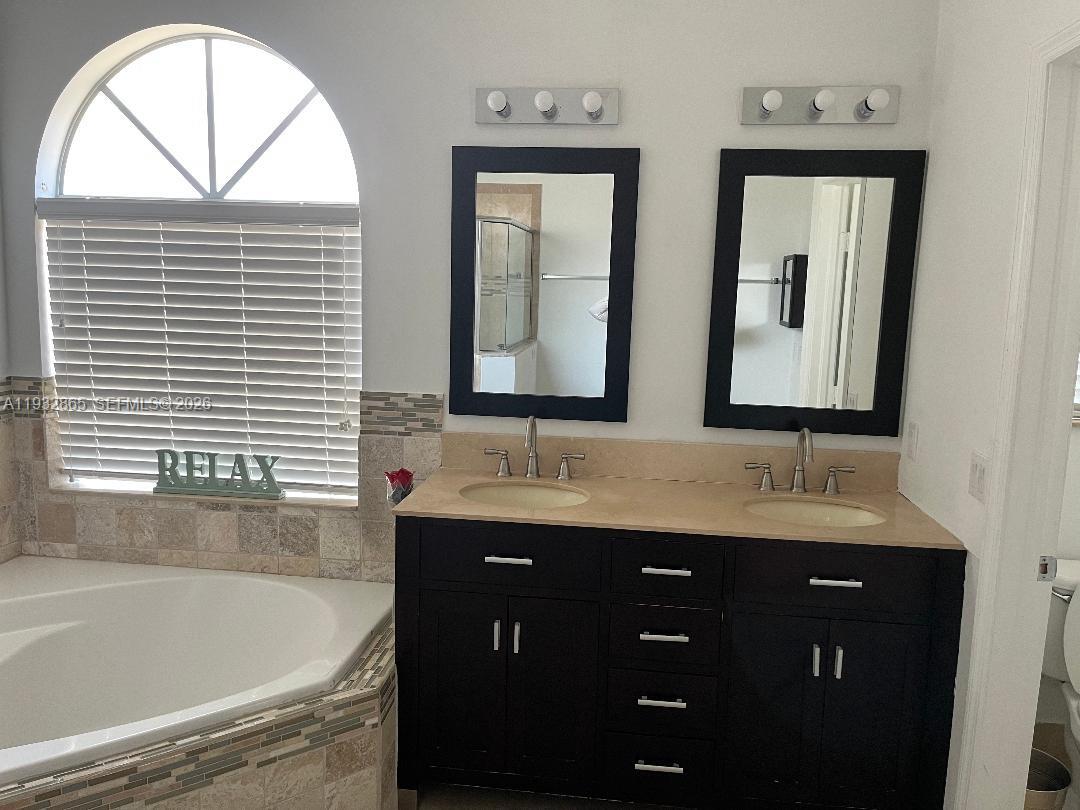 15205 Southwest 13th Terrace Miami, FL 33194 - Photo 10 of 12 a bathroom with a double vanity sink and mirror with bathtub