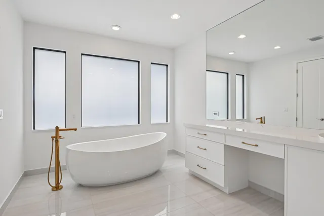 a spacious bathroom with a tub a double vanity sink and a mirror