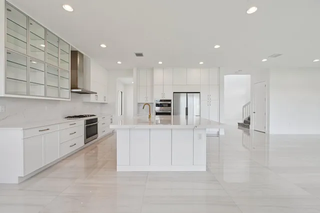 a large white kitchen with white cabinets and stainless steel appliances
