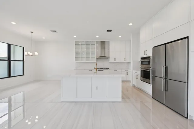 a large white kitchen with a sink stainless steel appliances and cabinets