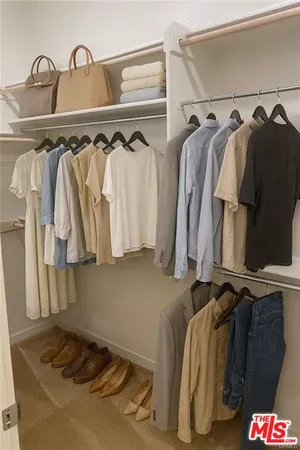 a view of walk in closet with clothes and shoes