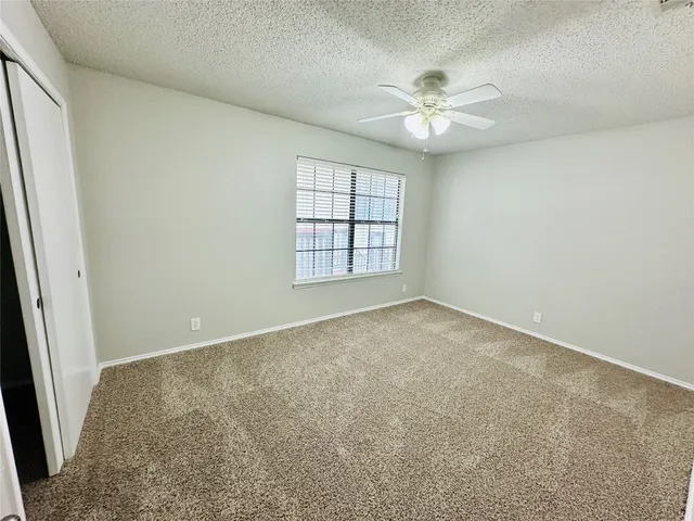 an empty room with windows and ceiling fan