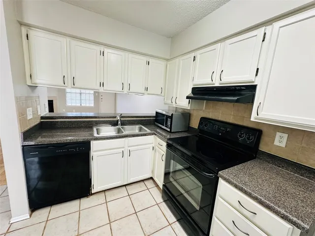 a kitchen with a stove and white cabinets