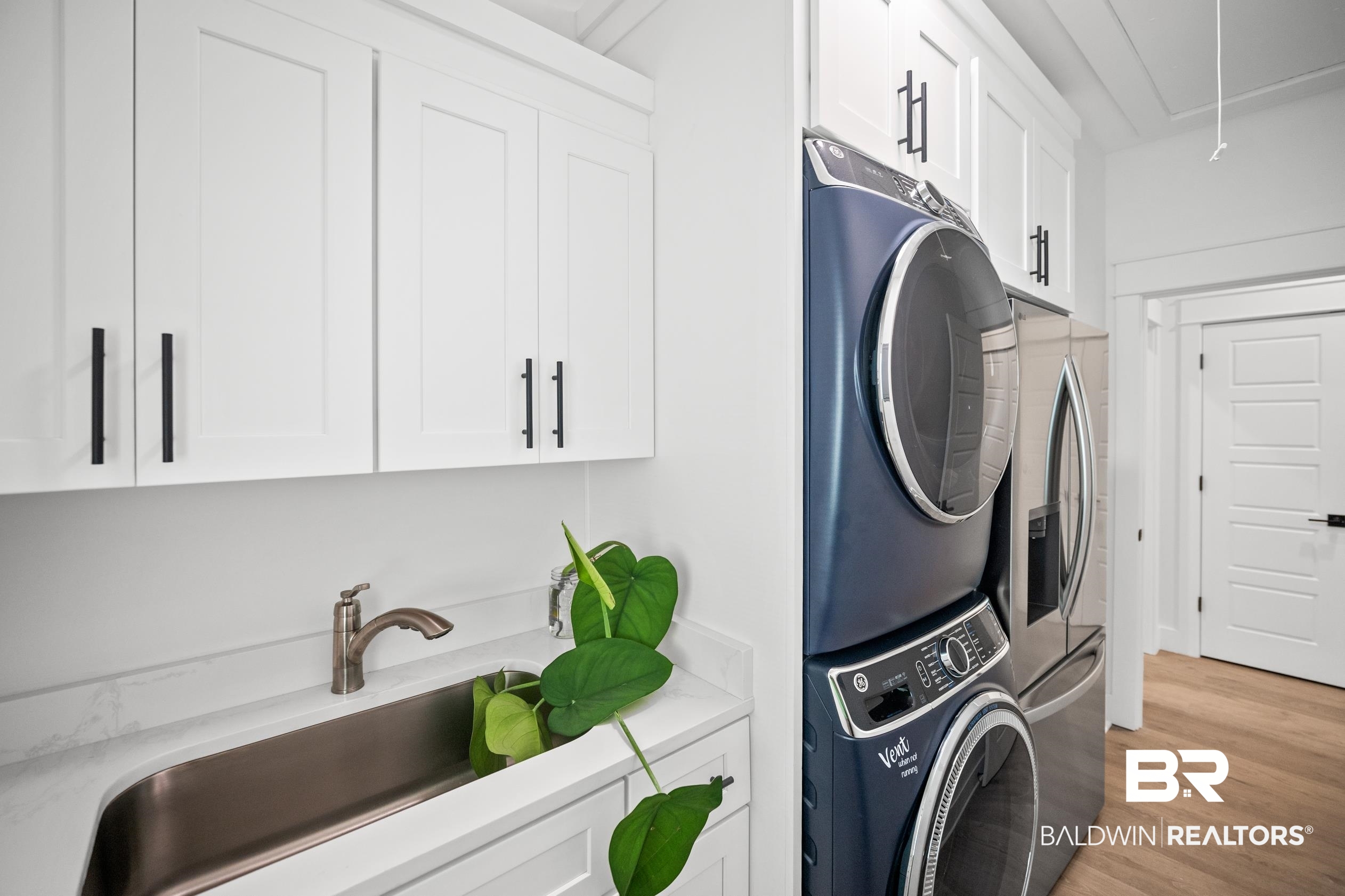 5501 Mobile Avenue Orange Beach, AL 36561 - Photo 20 of 40 Laundry room featuring attic access, cabinet space, stacked washing machine and dryer, and light wood-style floors