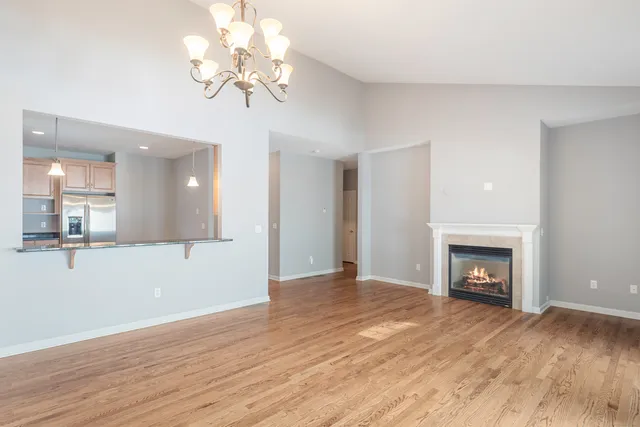 a view of an empty room with wooden floor fireplace and a window