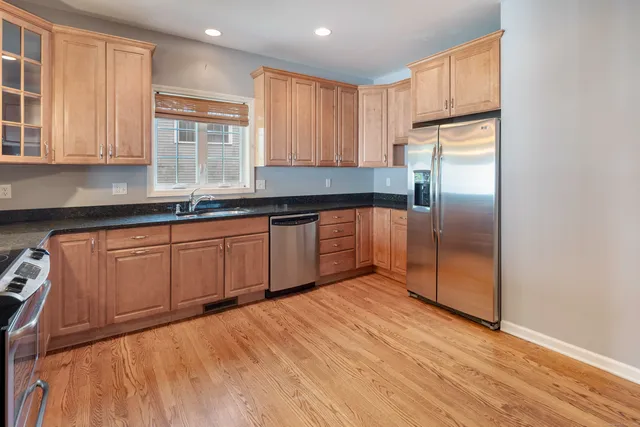 a kitchen with stainless steel appliances granite countertop a refrigerator a sink and dishwasher with wooden cabinets