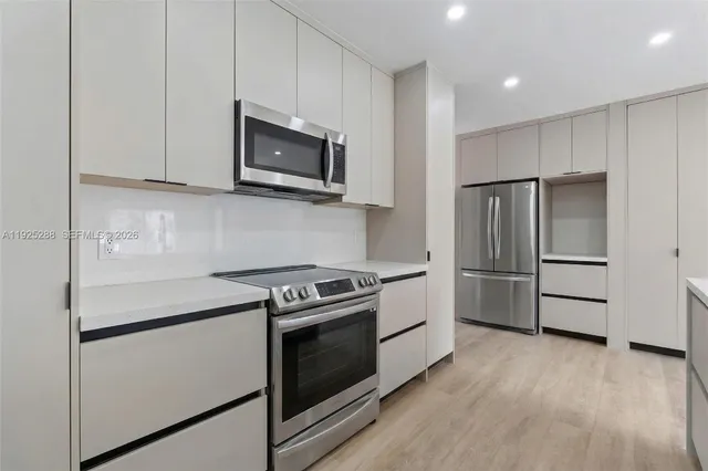 a kitchen with stainless steel appliances white cabinets and wooden floor
