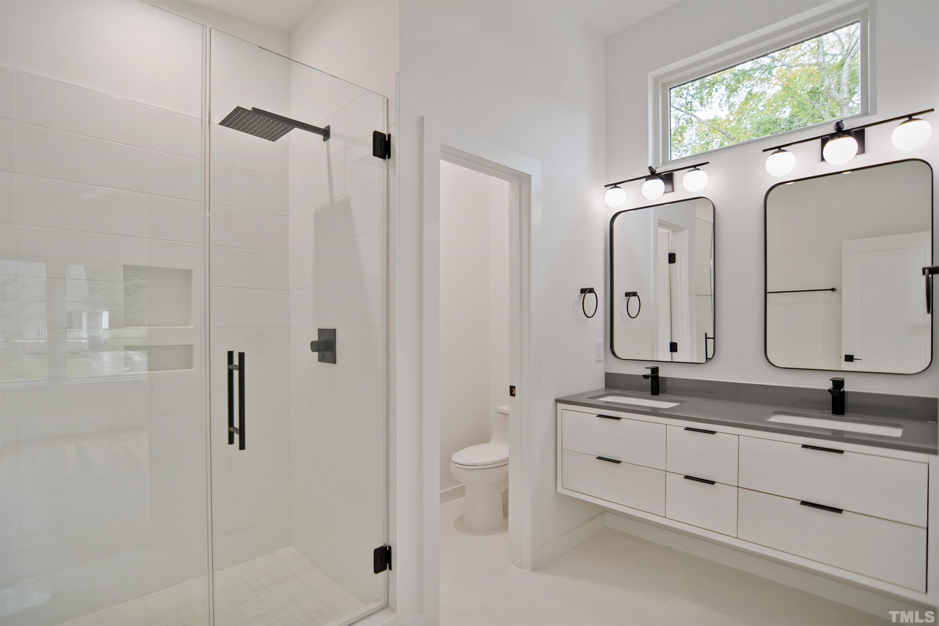 1306 East Lenoir Street Raleigh, NC 27610 - Photo 15 of 26 a bathroom with a double vanity sink toilet mirror and shower