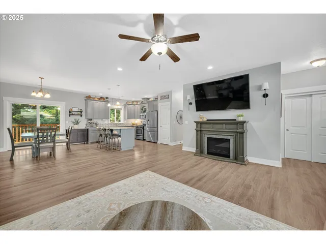 a view of a livingroom with fireplace wooden floor and a ceiling fan
