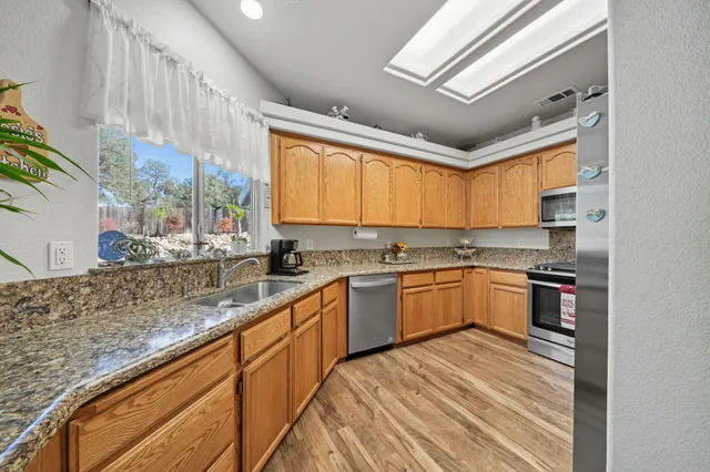 a kitchen with stainless steel appliances granite countertop a sink window and cabinets