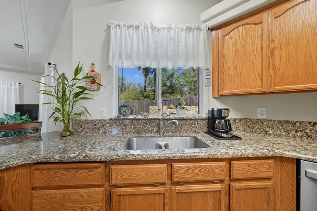 a kitchen with granite countertop a sink a counter top space and cabinets
