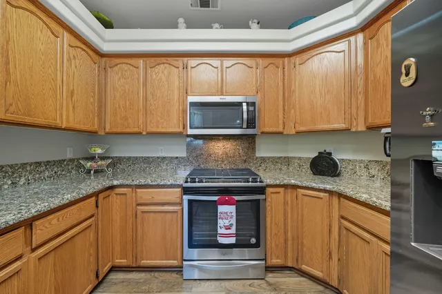 a kitchen with stainless steel appliances granite countertop wooden cabinets and a stove top oven